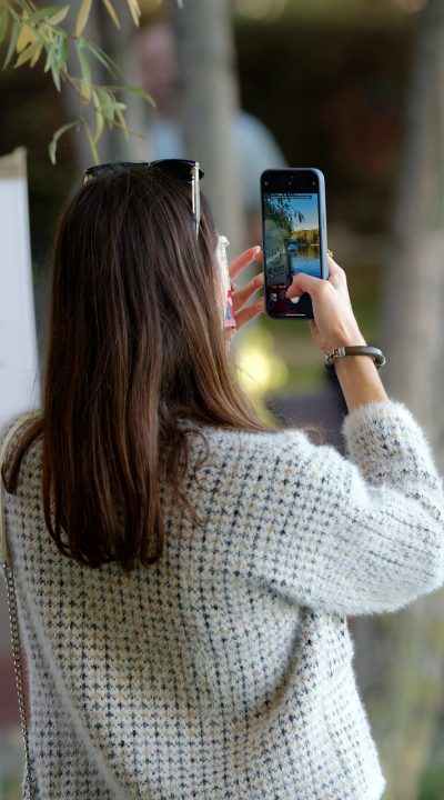 爱看影视 App 搜索页截屏，输入框里正在键入片名，下方列出多条匹配结果，屏幕反光映出桌面木纹